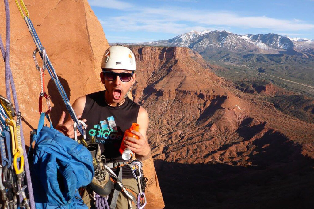 Male climber with a helmet and sunglasses on an exposed wall