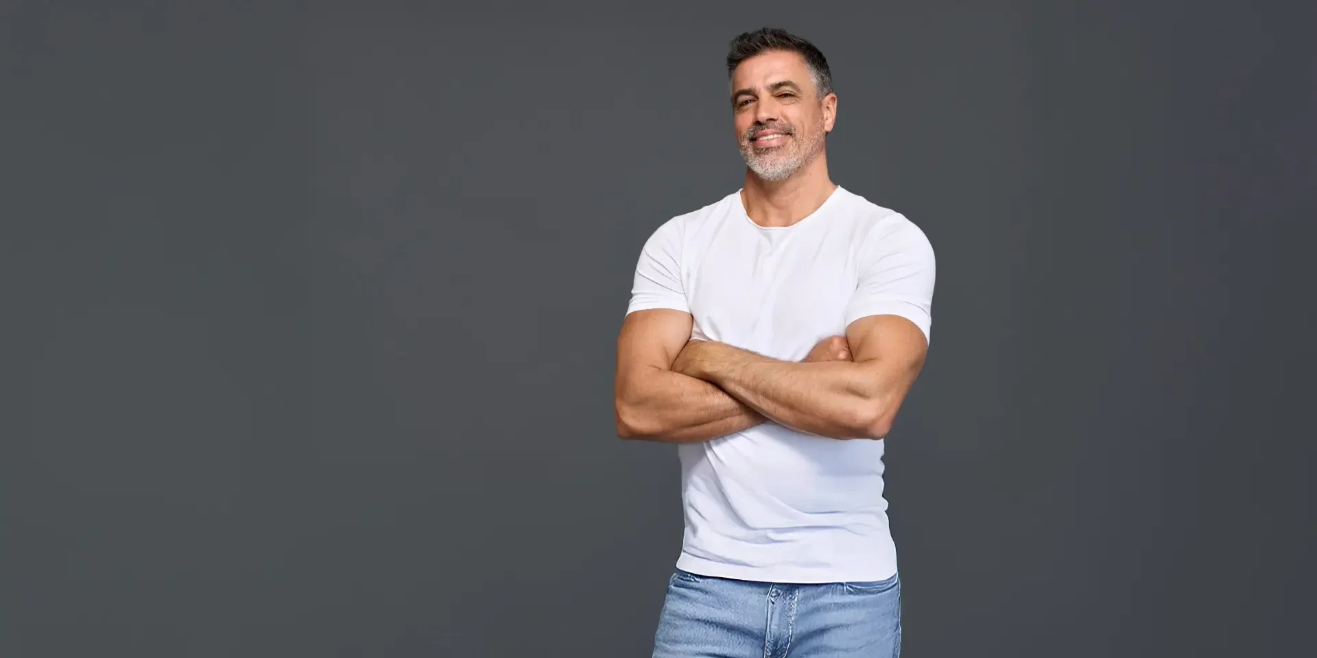 A happy older man with defined muscles in a white t-shirt on a black background