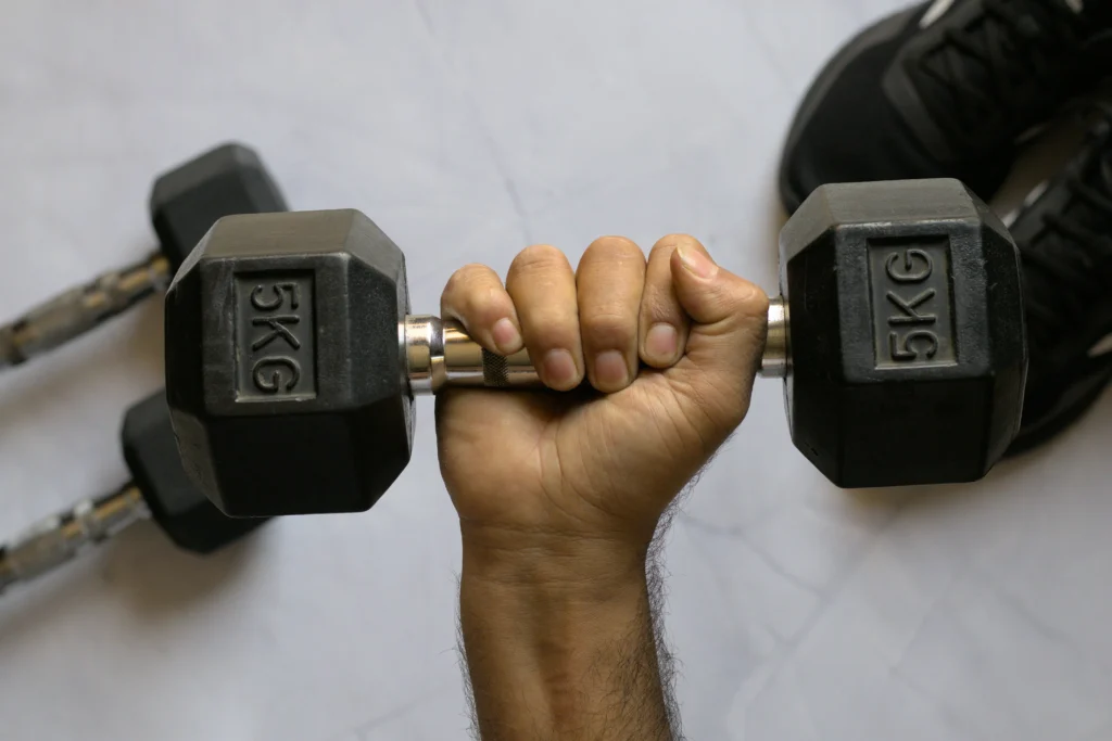 A dumbbell held in a hand over a white granite surface